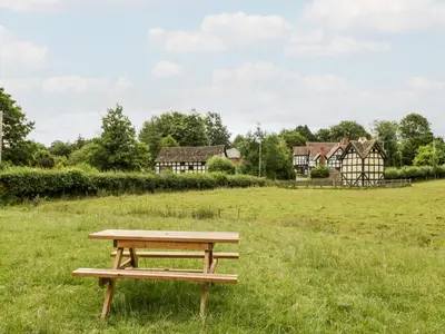 a picnic table in a field with houses in the background at Stable End in Pembridge