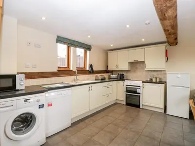 a kitchen with white cabinets and a washer and dryer at The Hop Kiln in Pembridge