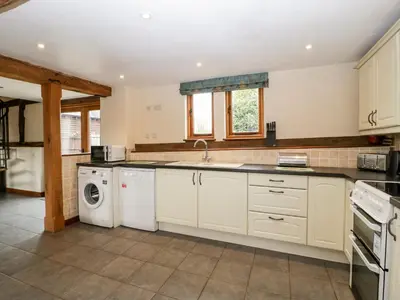 a kitchen with white cabinets and a washer and dryer at The Hop Kiln in Pembridge