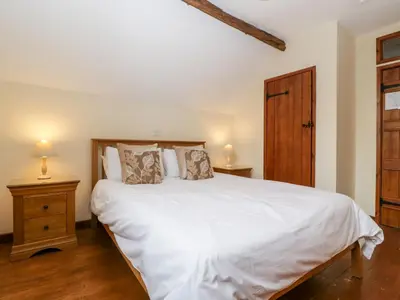 a bedroom with a white bed and a wooden cabinet at The Hop Kiln in Pembridge