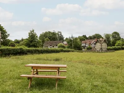 a picnic table in a field with houses in the background at The Hop Kiln in Pembridge