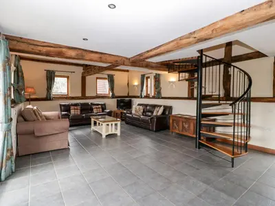 a living room with couches and a spiral staircase at The Hop Kiln in Pembridge