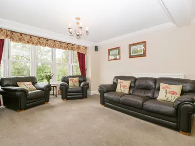 a living room with a leather couch and two chairs at The Croft in Vowchurch