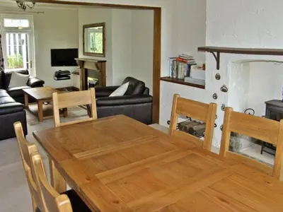 a living room with a wooden table and a couch at Railway Cottage in Fairbourne