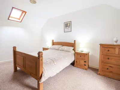 a bedroom with a wooden bed and a dresser at Y Bwthyn in Llanbedr