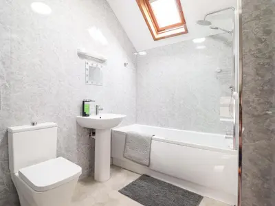 a bathroom with a white toilet and a sink and a shower at Y Bwthyn in Llanbedr