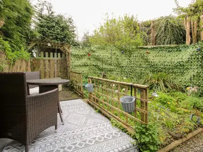 a garden with a wooden fence and a table and a hedge at The Log Cabin in Adforton