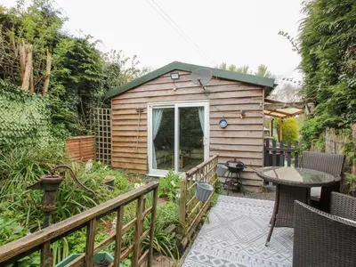 a small wooden cabin with a table and a patio at The Log Cabin in Adforton