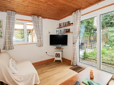 a living room with a tv and a large window at The Log Cabin in Adforton