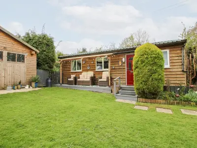 a log home with a red door and a yard at The Log Cabin in Adforton