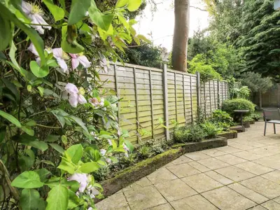 a fence with pink flowers next to a patio at Inglenook in Ludlow