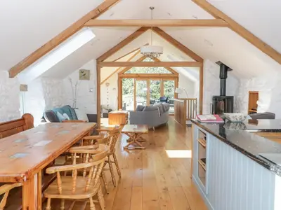 a kitchen and living room with a large wooden table at Tyn Llwyn in Gwyddelwern