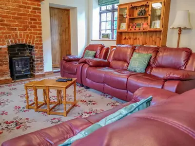 a living room with red leather couches and a table at Tailor's Cottage in Abbey-Cwmhir
