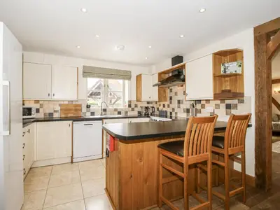 a kitchen with white cabinets and a island with two chairs at The Milking Parlour in Craven Arms