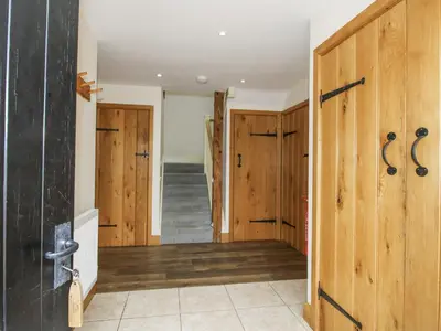 a hallway with wooden doors and a staircase at The Milking Parlour in Craven Arms