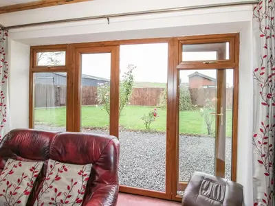 a leather couch sitting in front of a sliding glass door at The Stable in Craven Arms