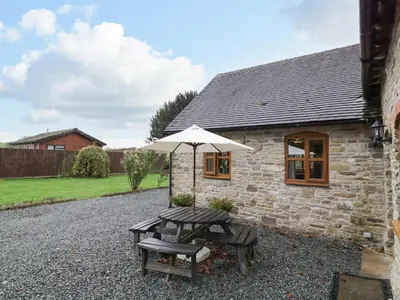 a stone cottage with an umbrella and a picnic table at The Stable in Craven Arms