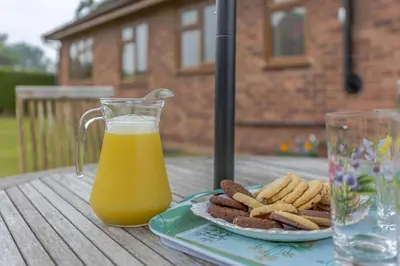 a glass pitcher of orange juice next to a plate of cookies at Meadow Lea in Leominster