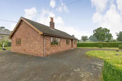 a brick house with a gravel parking lot at Meadow Lea in Leominster