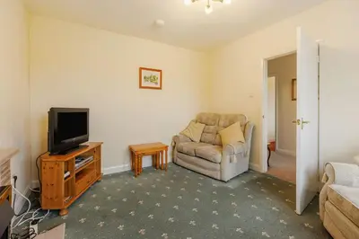 a living room with a chair and a television at Meadow Lea in Leominster