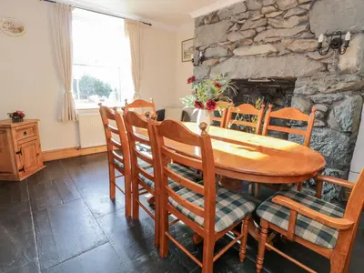 a dining room with a table and chairs and a stone fireplace at Tyddyn in Dyffryn