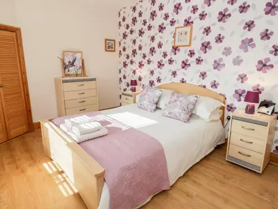 a bedroom with a bed with purple flowers on the wall at Tyddyn in Dyffryn