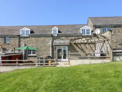 a stone house with a green lawn in front of it at Mill Cottage in Ciliau-Aeron