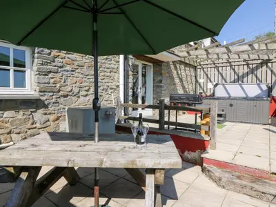 a wooden table with a green umbrella on a patio at Mill Cottage in Ciliau-Aeron