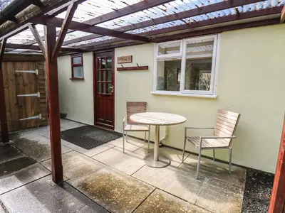 a patio with a table and two chairs and a window at Trout Cottage in Llandrindod Wells