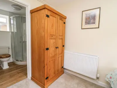 a bathroom with a wooden cabinet next to a toilet at Trout Cottage in Llandrindod Wells