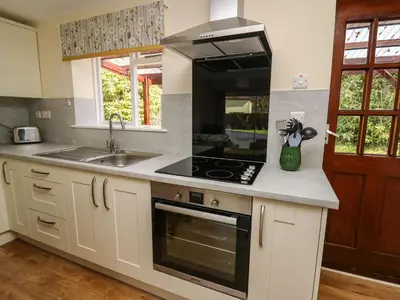 a kitchen with a stove top oven next to a sink at Trout Cottage in Llandrindod Wells