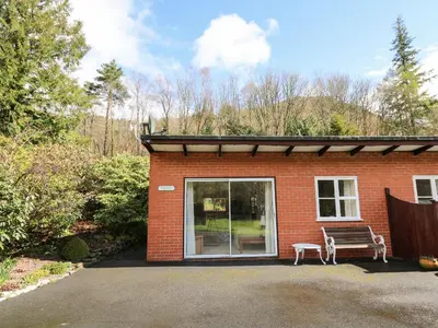a red brick house with a bench in front of it at Trout Cottage in Llandrindod Wells