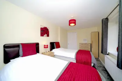 two beds in a small room with red blankets at Lower Lodge in Cardeston