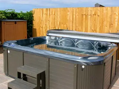 an outdoor kitchen with a hot tub on a patio at Lower Lodge in Cardeston