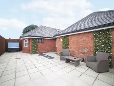 a courtyard with two chairs and a brick building at Lower Lodge in Cardeston