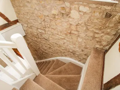 a staircase in a building with a stone wall at The Coach House in Ludlow