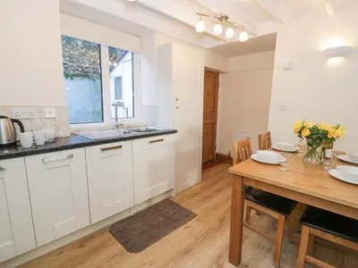 a kitchen with white cabinets and a wooden table at Ty Gwyn in Aberdyfi