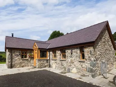 a large stone house with a roof at Beudy in Llangwm