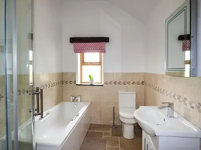 a bathroom with a tub and a toilet and a sink at Beudy in Llangwm