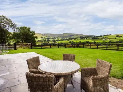 a patio with a table and chairs and a field at Beudy in Llangwm