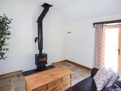 a living room with a wood stove in a room at Beudy in Llangwm