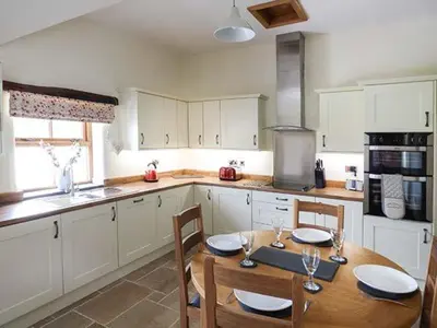 a kitchen with a wooden table with chairs and a dining room at Beudy in Llangwm