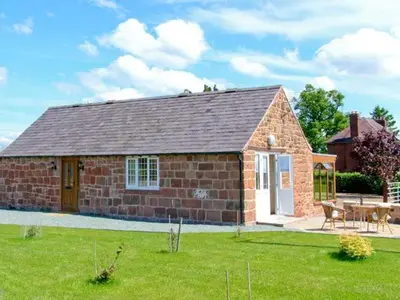 a brick house with a table in a yard at Byre Cottage in Nesscliffe