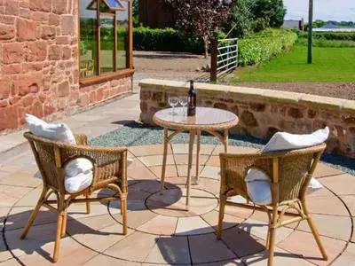 a table and two chairs and a table with a bottle of wine at Byre Cottage in Nesscliffe