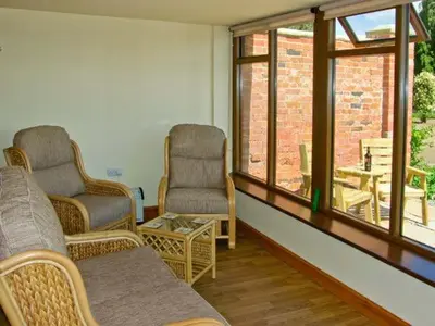 a living room with two chairs and a table at Byre Cottage in Nesscliffe