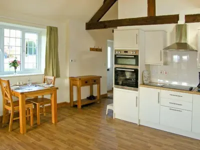 a kitchen with a wooden table and a kitchen with a dining room at Byre Cottage in Nesscliffe