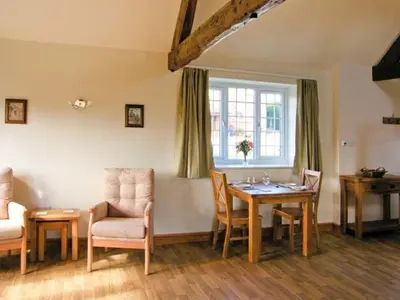 a living room with a table and chairs and a window at Byre Cottage in Nesscliffe