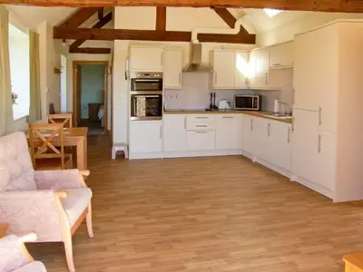 a kitchen with white cabinets and a couch in a room at Byre Cottage in Nesscliffe