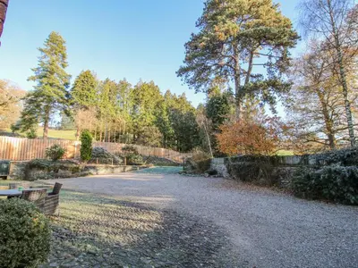 a gravel driveway in a garden with a fence at The Coach House in Oswestry