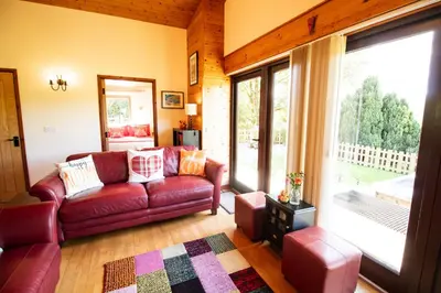 a living room with a couch and a large window at Sycamore Lodge in Rhayader